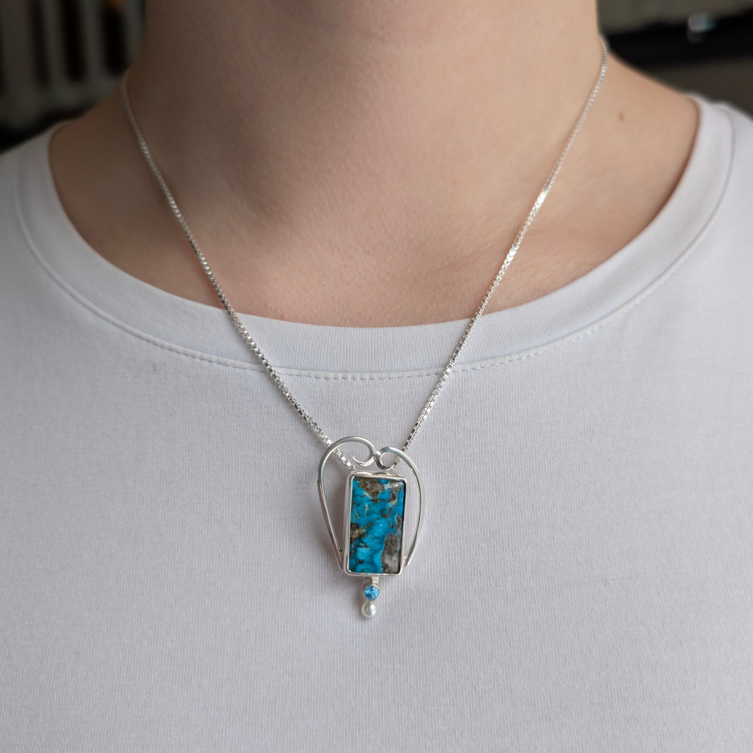 Sterling Silver pendant with Turquoise, Swiss Blue Topaz and Freshwater Pearl, includes an 18 inch Sterling Silver box chain on a model.