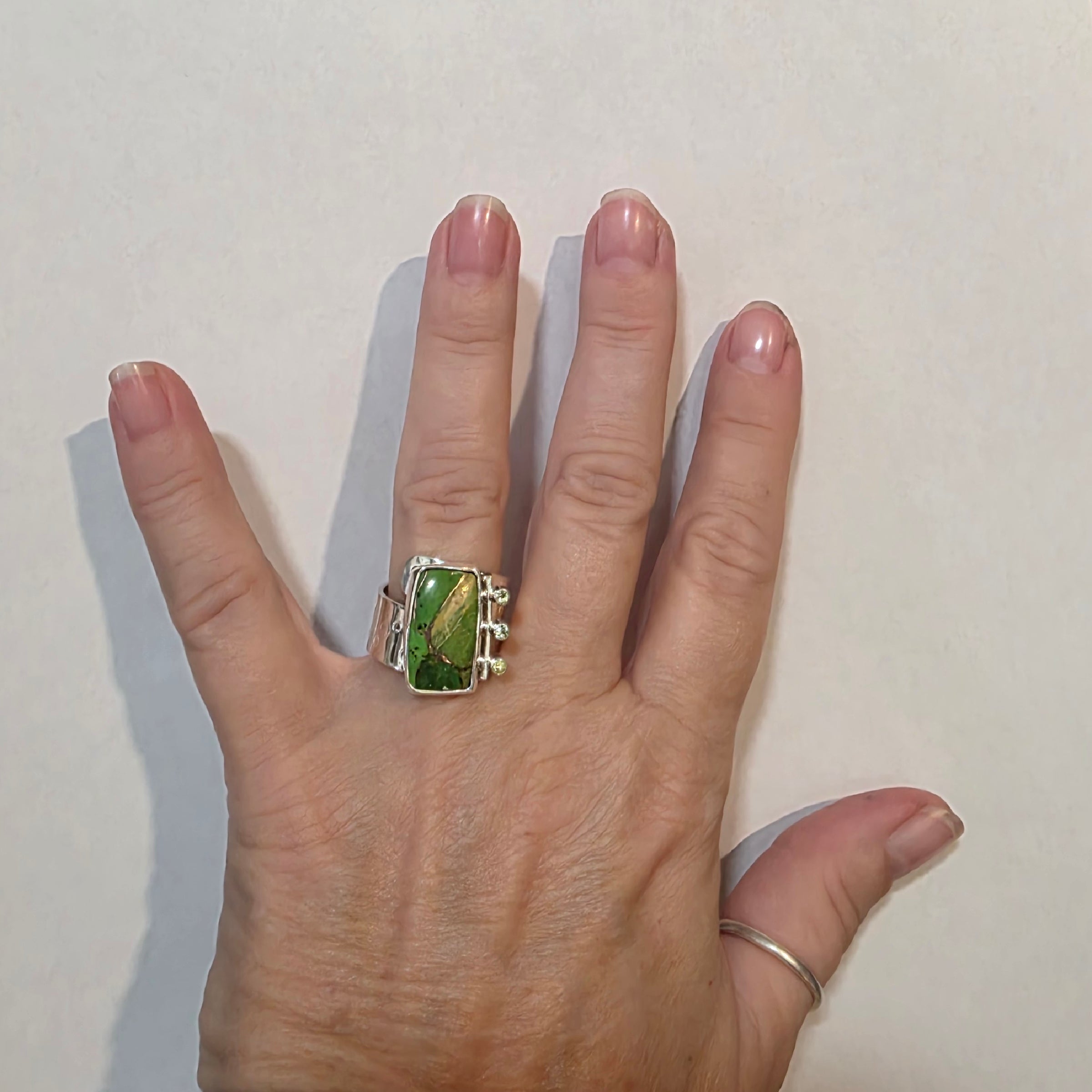 Adjustable Sterling Ring with Mohave Turquoise and Peridot on a model's hand.