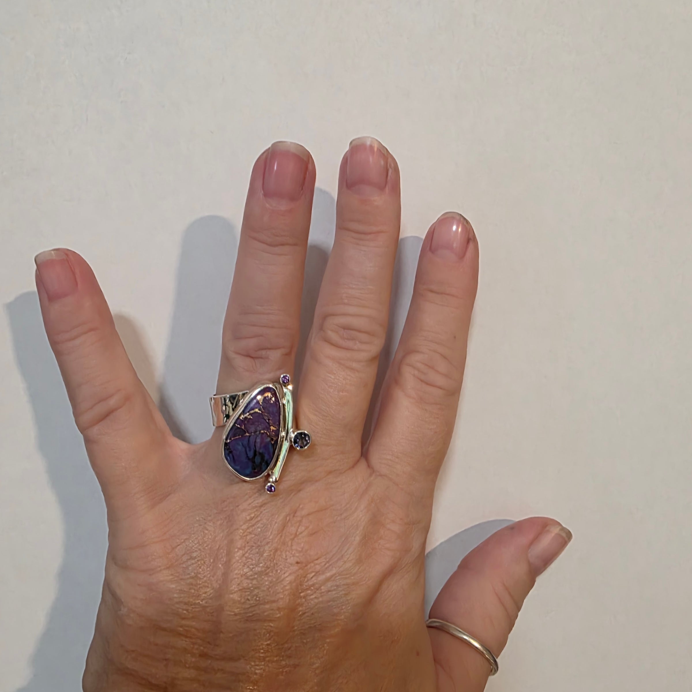 Adjustable Sterling ring with purple Mohave Turquoise, Iolite and Amethyst on a models hand.