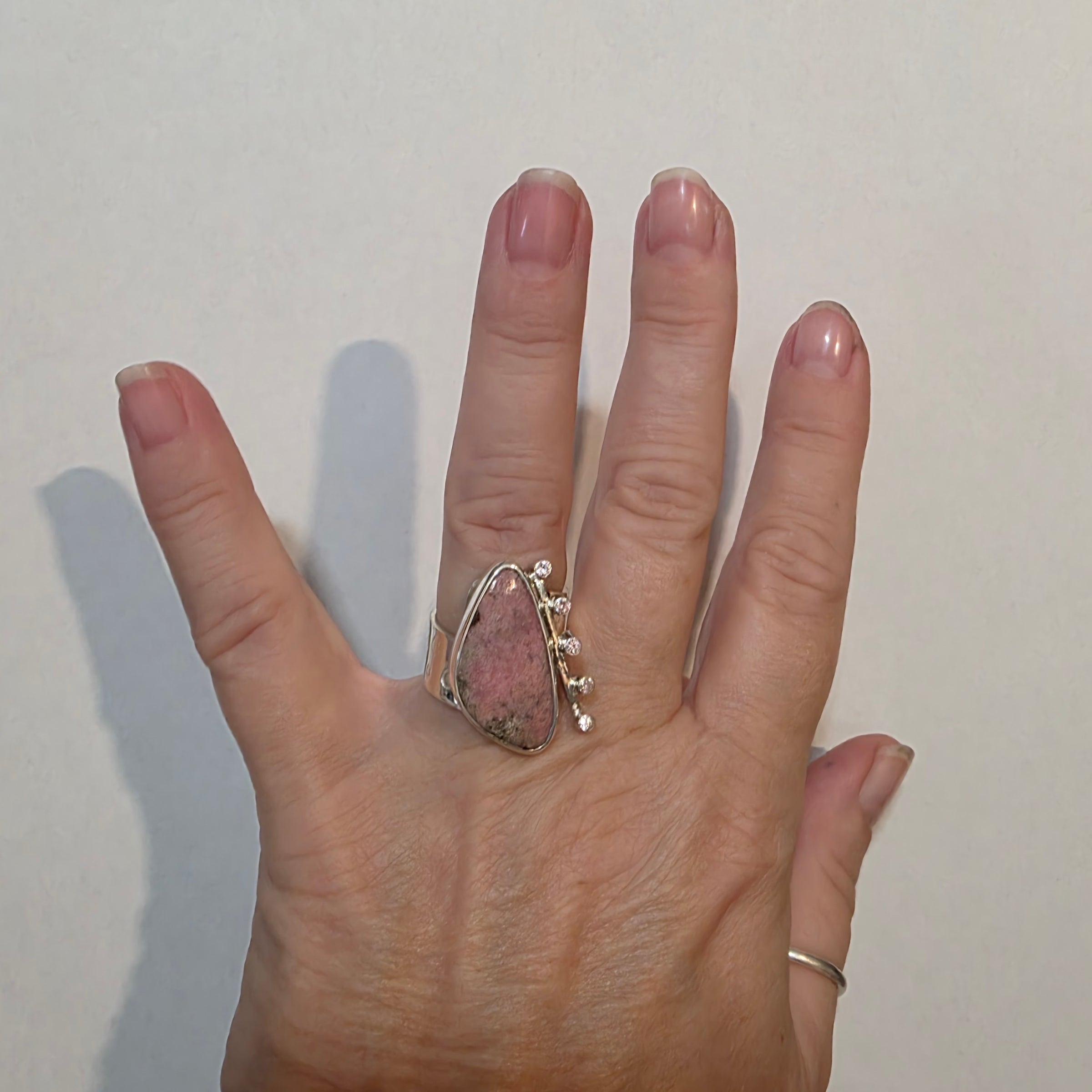 Adjustable Sterling ring with pink Cobalto Calcite and Pink Cubic Zirconia on a model's hand.
