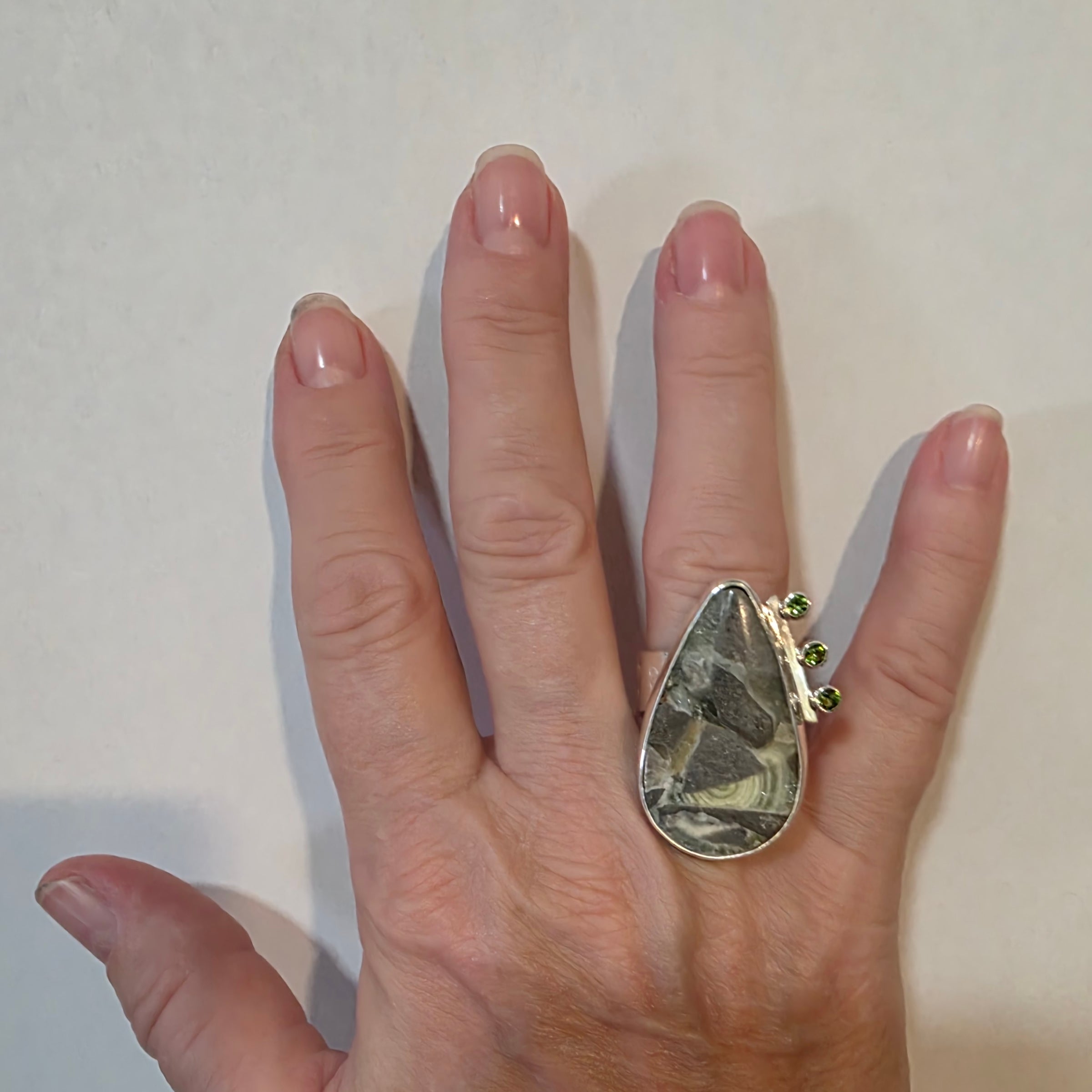 Adjustable Sterling ring with green Wavelight Jasper and Green Tourmaline Cubic Zirconia on a model's hand.