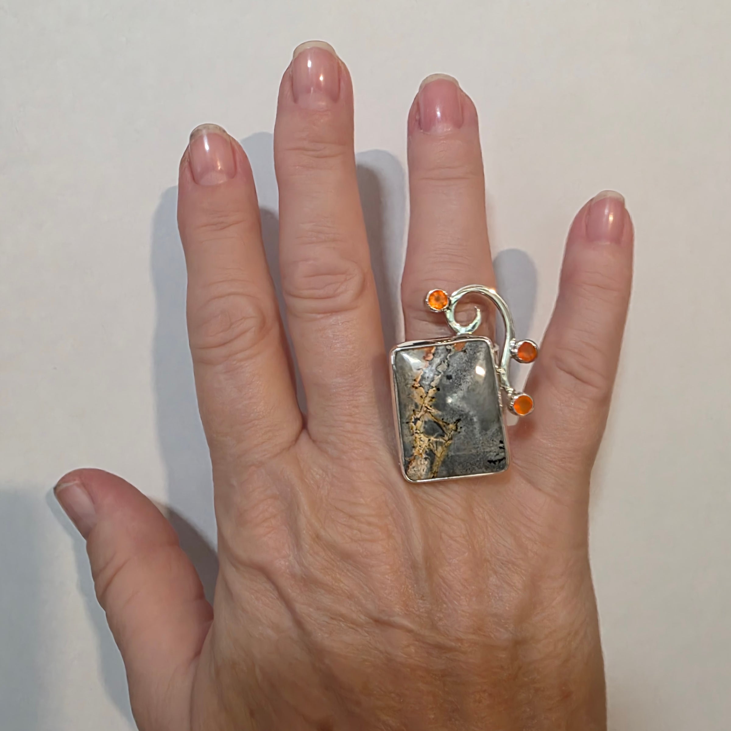 Adjustable Sterling ring with Maligano Jasper and Carnelian on a model's hand.